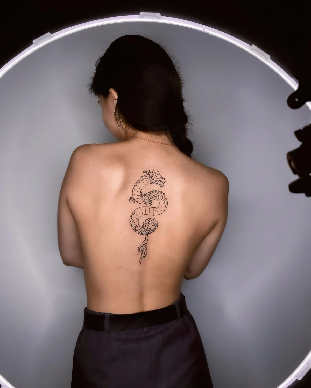 dessin dragon symbolisme tattoo dos femme pantalon noir cheveux tresse