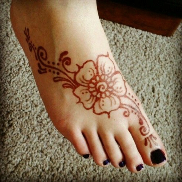 dessin henné, dessin de fleur orange sur le pied, vernis à ongles noir
