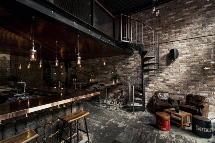 meuble industriel, bar en cuivre, tabouret de bar en bois et fer, plancher gris, lampes suspendues en verre, plantes vertes
