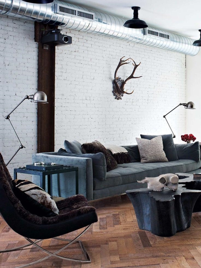 meuble industriel, canapé bleu foncé, pipes apparents, coussins décoratifs, lampes en métal, murs en blanc