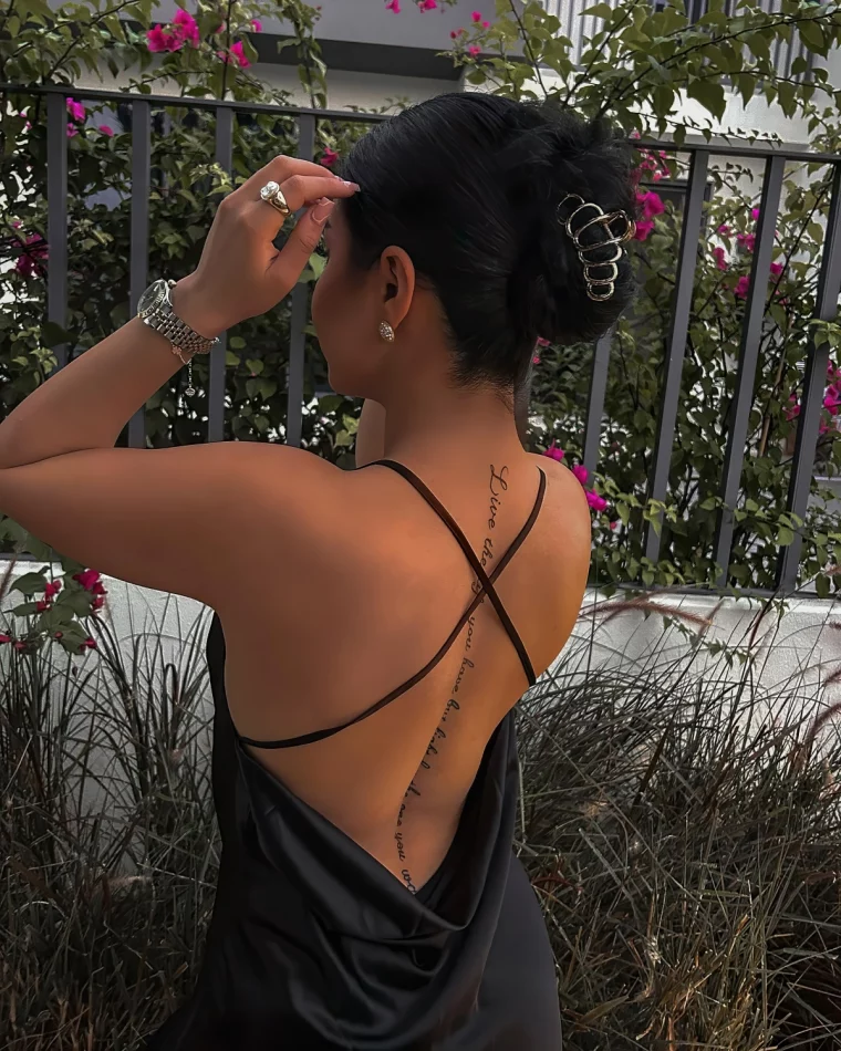 ecriture tatouage colonne vertebrale femme robe noire bretelles fines