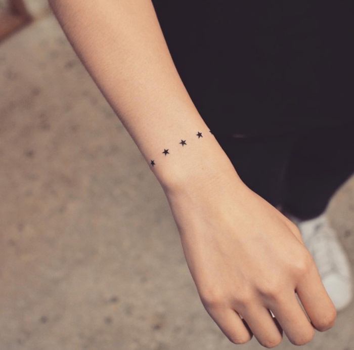 idée de petit tatouage femme, un bracelet d'étoiles noires en chapelet, tattoo femme moderne