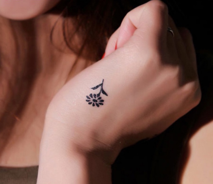 idée de tatouage petit femme main, une fleur noire, modele de tatouage minimaliste par excellence