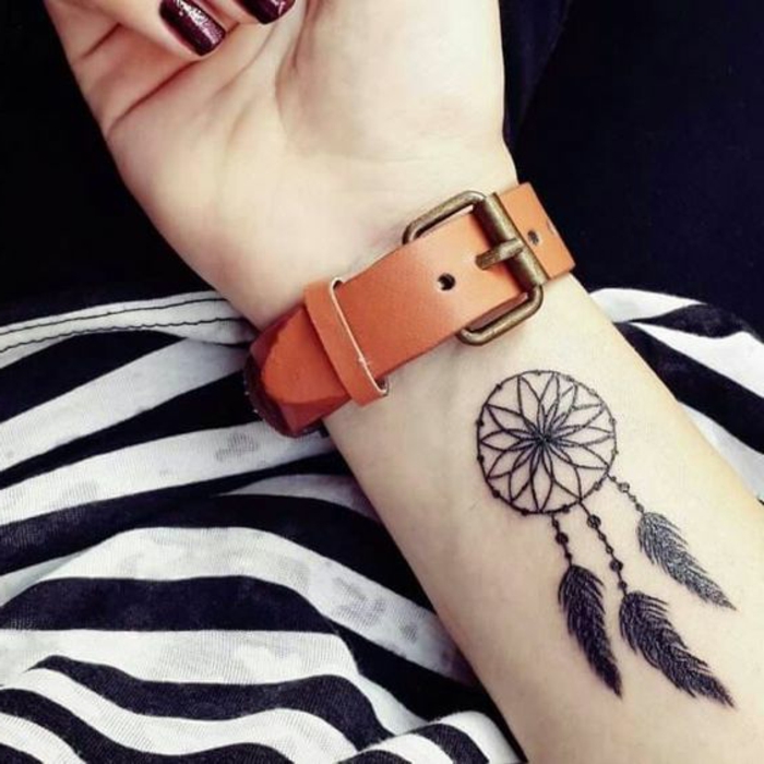 tatouage attrape reve avant bras graphique, encre noir, rosace, plumes, perles, une montre marron, comment se tatouer idée femme