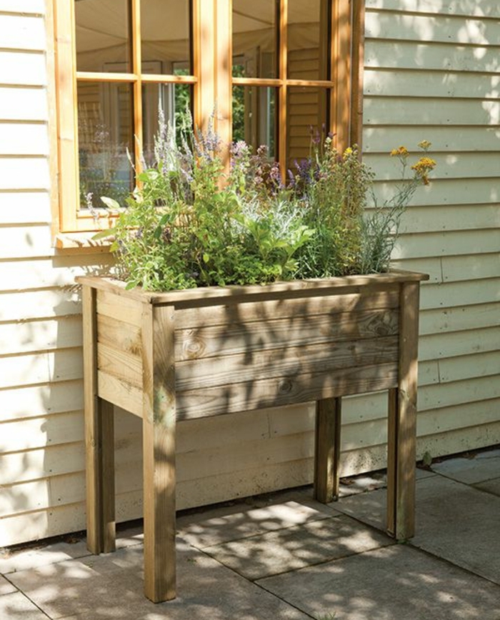 idée de bricolage bac a fleur en palette à pieds, des plantes vertes plantées dans une jardiniere placée à l extérieur, adossée à une maison