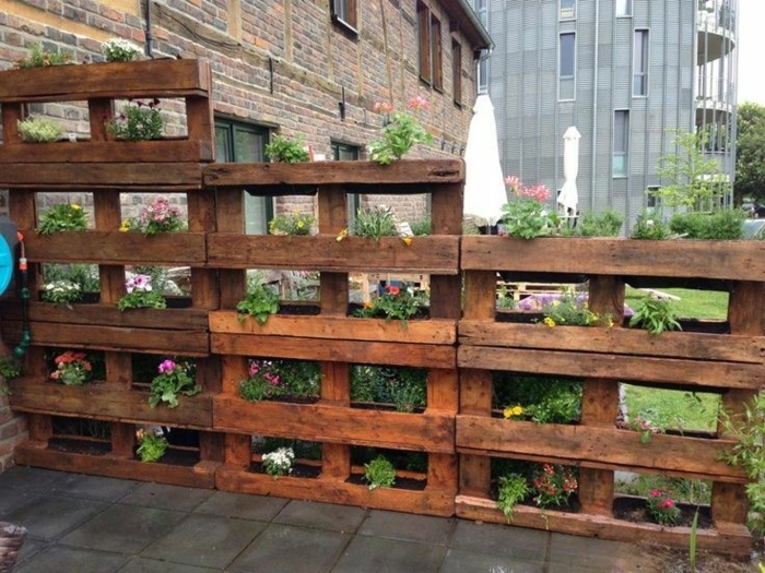 jardiniere palette asymétrique, mur vegetal palette de bois, des fleurs plantés dans le cavités entre les plamches de bois, cloison, mur de sépration