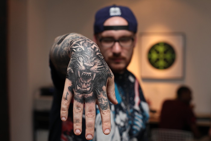 tatouage bras homme, design tattoo, motifs d'animaux, tigre, casquette bleu foncé, tatouage homme
