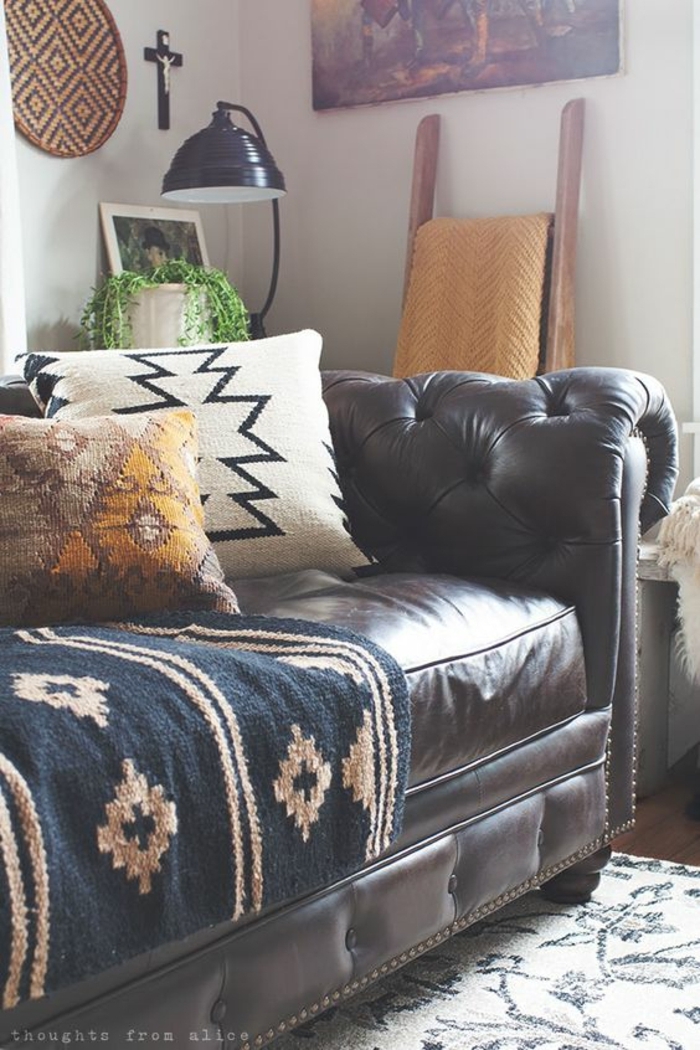 motif azteque, sofa en cuir marron, carpette et coussins ethniques, mur gris pâle