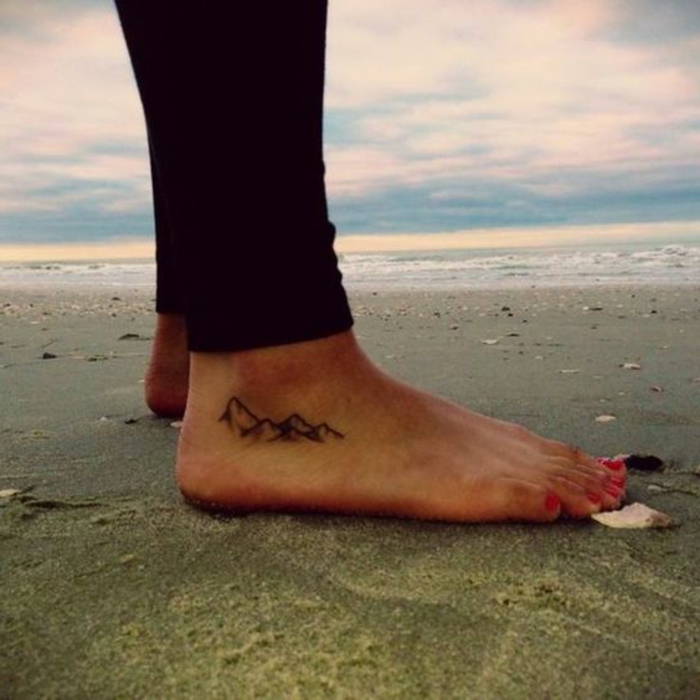 petit tatouage discret, tatouage au piedn une femme sur la plage avec tatoo montagne