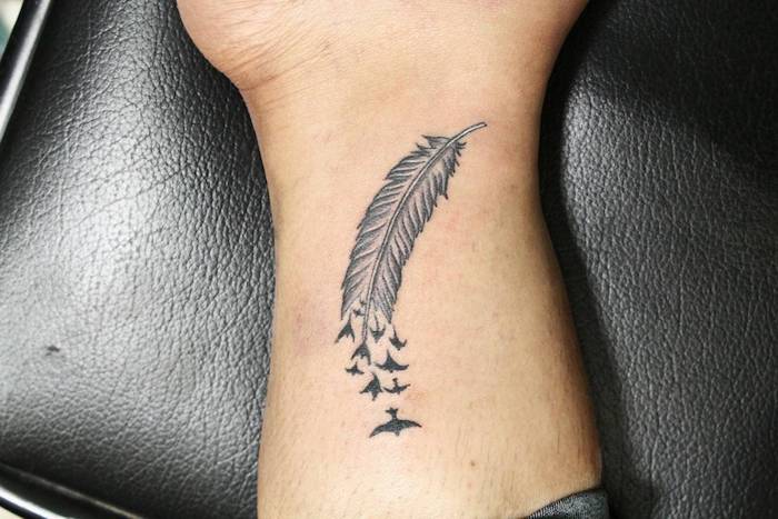 tatouage homme, surface en cuir noir, dessin en encre sur la peau, motifs plumes avec oiseaux volants