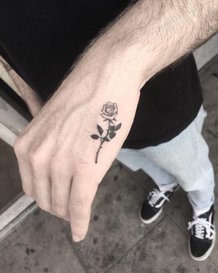 petit tatouage homme, fleur sur la main, rose noire, dessin graphique minimaliste