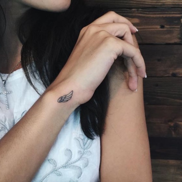 idée petit tatouage poignet pour femme, une aile graphique en noir, cheveux chatain foncé