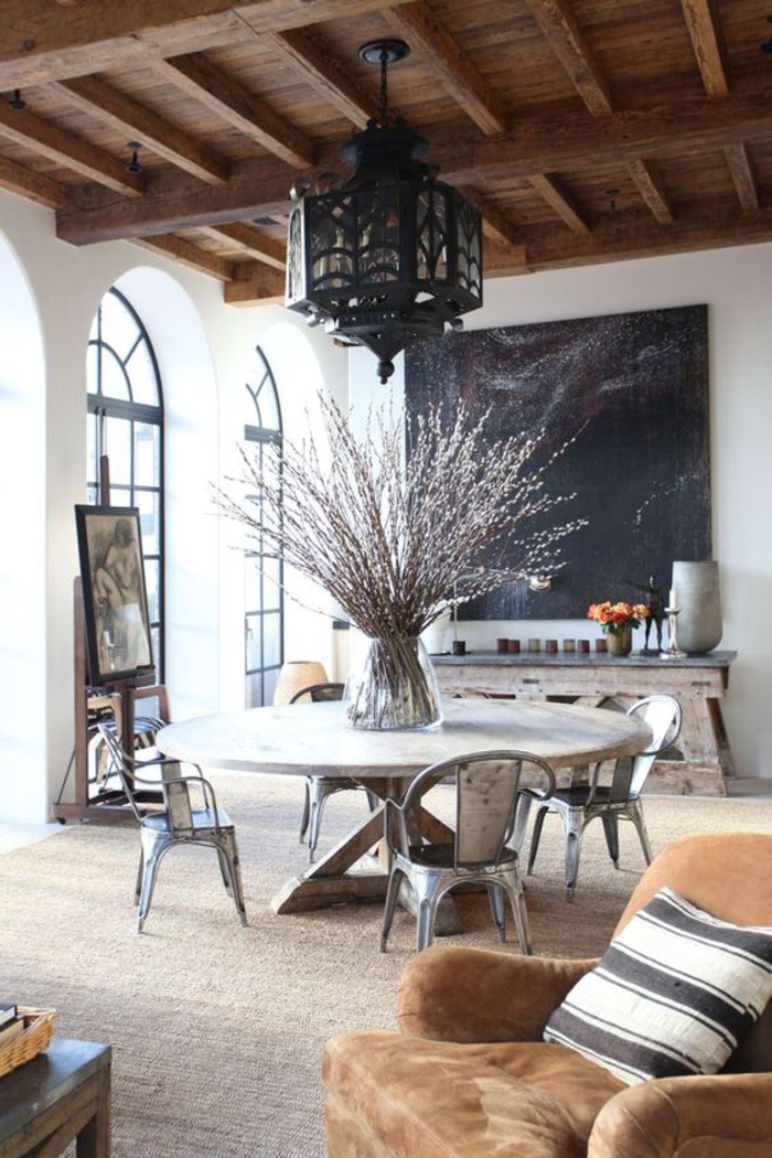 un grand salon qui mixe les styles scandinave et ethnique chic, des chaises industrielles associées à une table en bois massif
