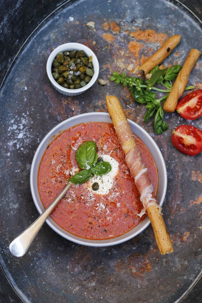 une soupe froide aux tomates et aux câpres qu'on sert froide ou chaude, gaspacho accompagné de gressins au prosciutto