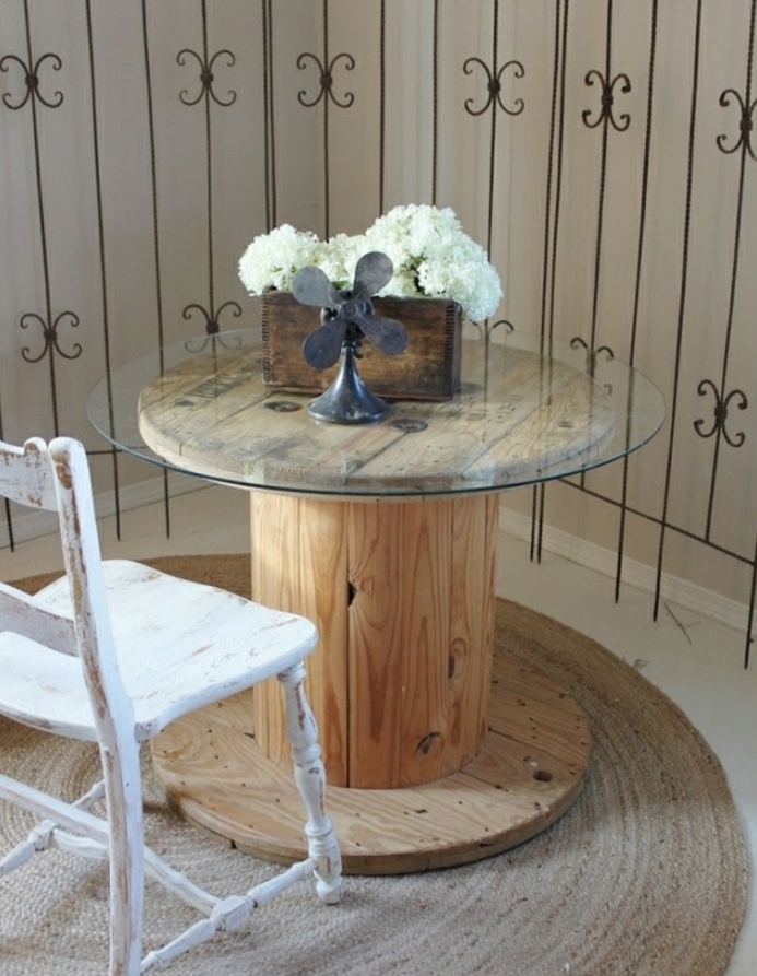 table basse touret avec un plateau en verre, bac en bois, rangement bouquet de fleurs et chaise blanche patinée