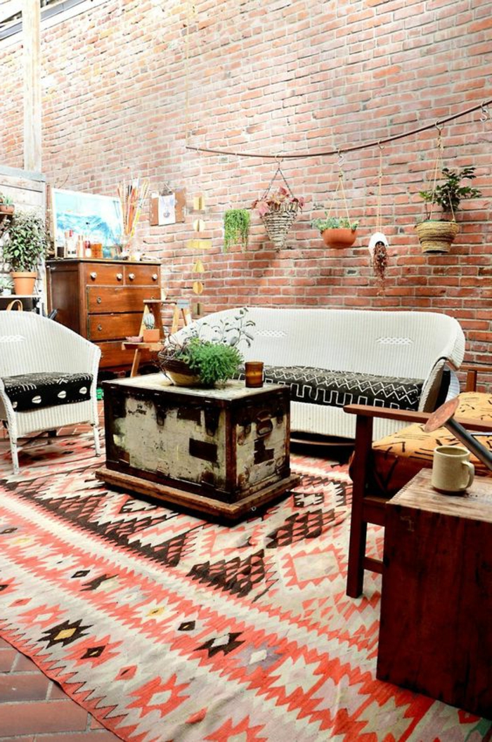 tapis ethnique, mobilier vintage, valise vintage, mur en briques, pots de fleurs suspendus