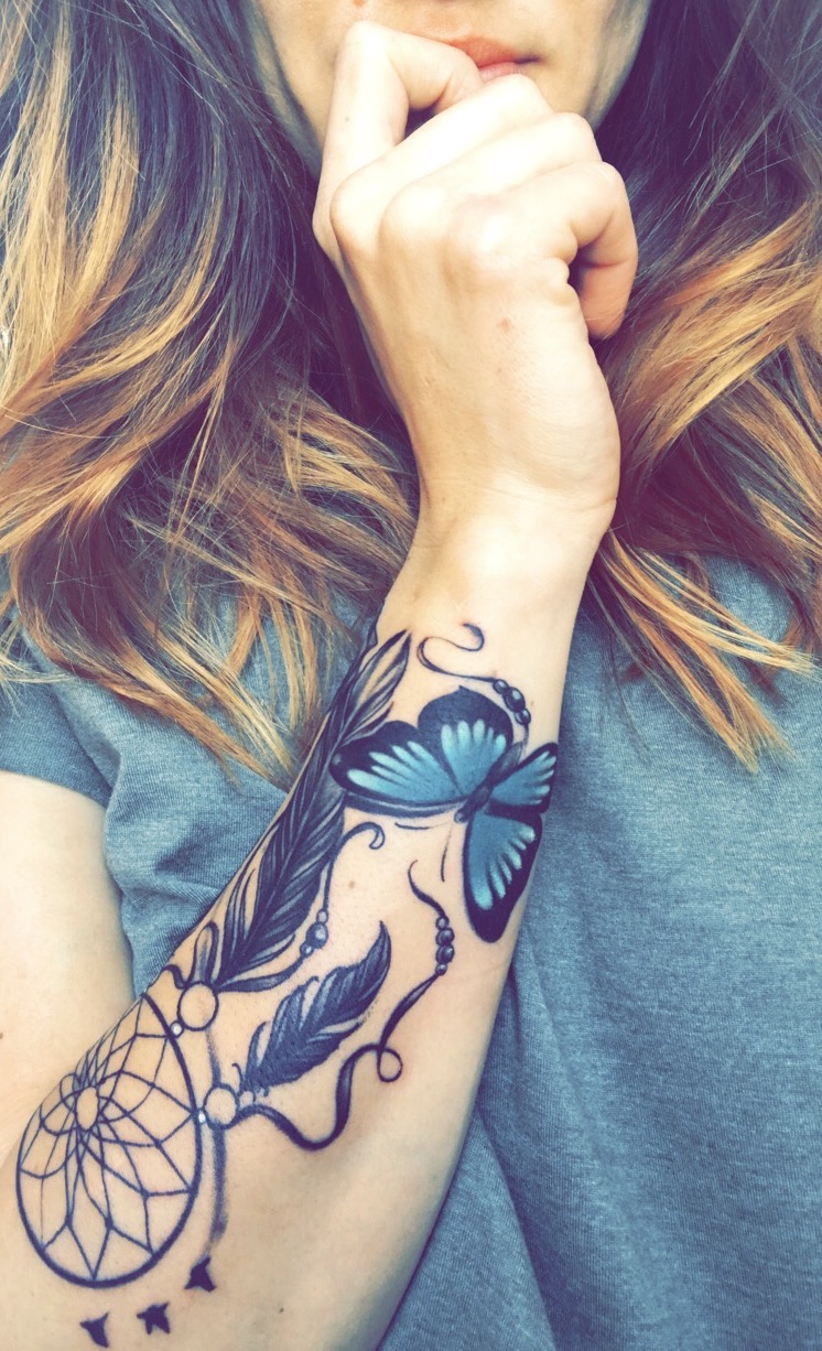 tatouage attrape reve graphique., cerceau filet et plumes noires et dessin papillon en noir et bleu, bras femme
