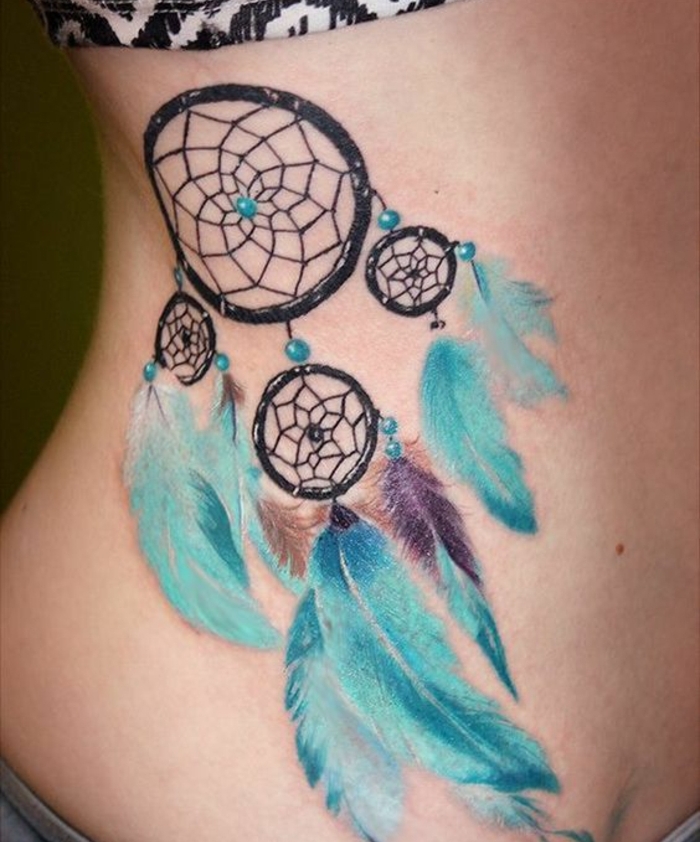 idée de tatouage attrape reve sur les côtes, quatre cerceaux noirs de tailles diverses, perles et plumes bleues, petites touches de couleur mauve et marron