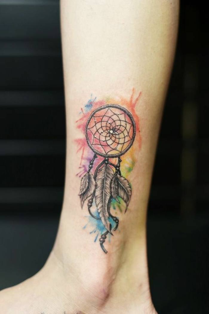 tatouage attrape reve sur la jambe, capteur de reve graphique, nuage rouge, mauve, bleu, jaune, vert, plumes en noir et blanc