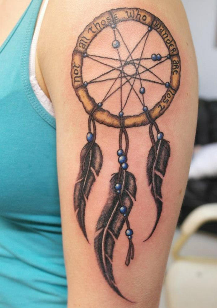 tatouage attrape-rêve, cerceau marron, plumes graphiques, encre noire, perles bleues, filet simple, idée de tatouage femme épaule