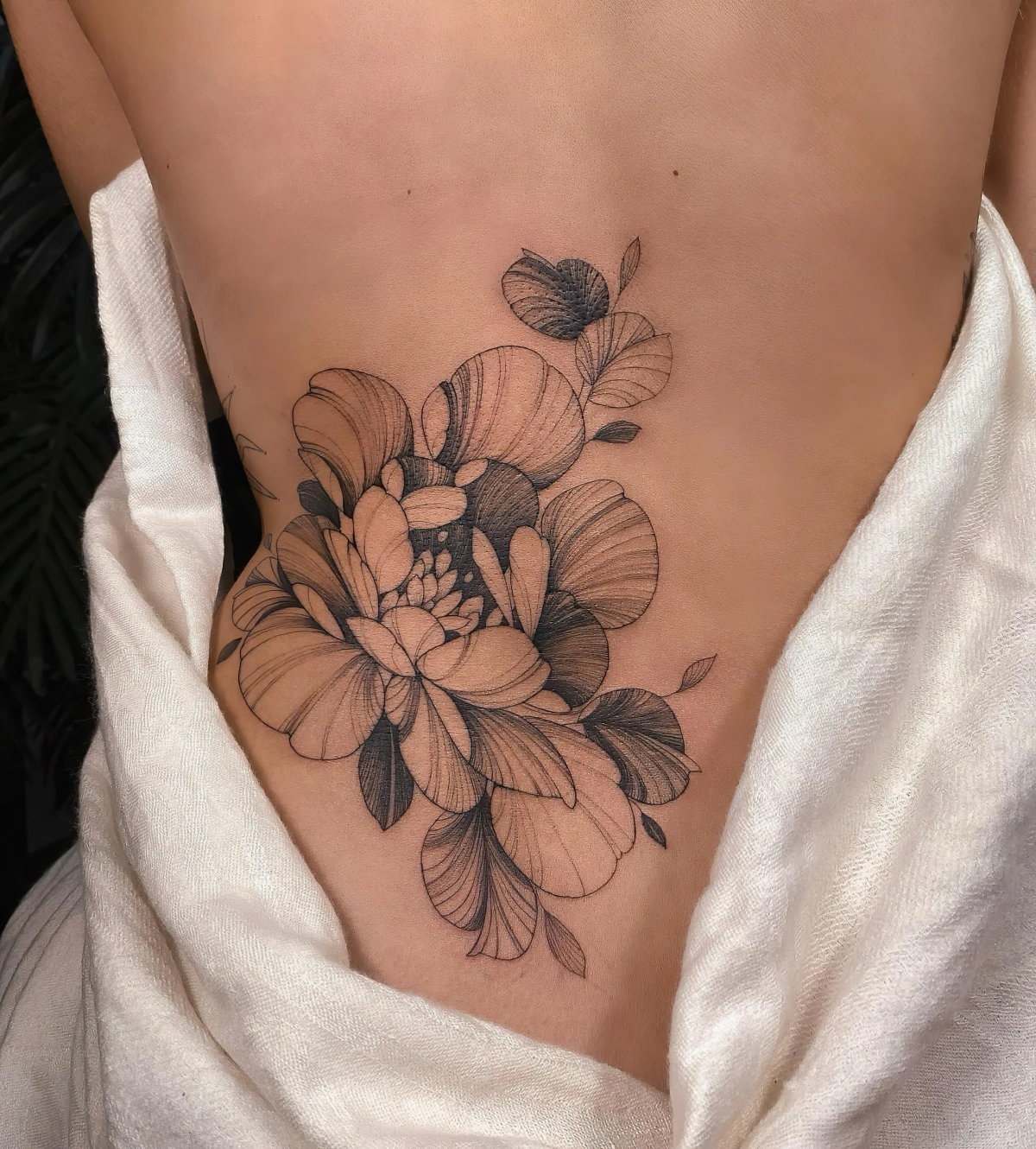 tatouage bas du dos femme fleurs petales art corporel dessin noir