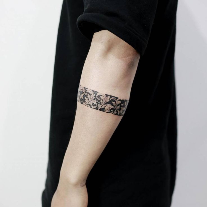 tatouage bracelet sur le bras, une bande noire à motifs floraux vintage, idée de tatouage homme