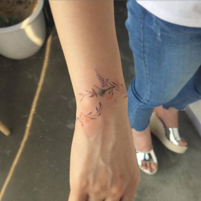 tatouage bracelet poignet pour femme, une branche fleurie coloré autour du poignet, idée de tattoo élégant