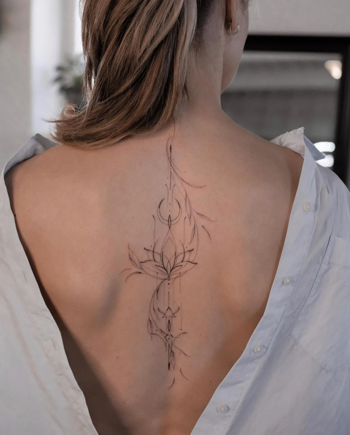 tatouage dos femme lotus fleur feuilles lune motifs dessin corps