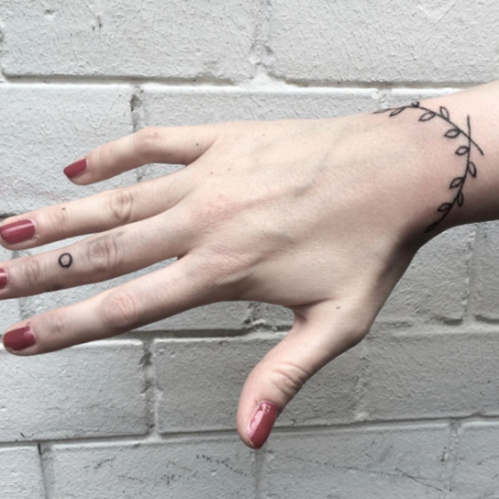 idée de tatouage bracelet poignet pour femme, une branche à feuilles graphique, encre noire