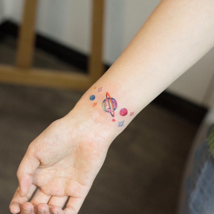 modèle de tatouage femme coloré, les planètes du système solaire, gravitant sur le poignet