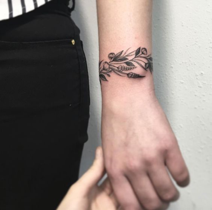 tatouage femme bracelet au poignet, une branche fleurie, dessin encre noire, tatouage feminin