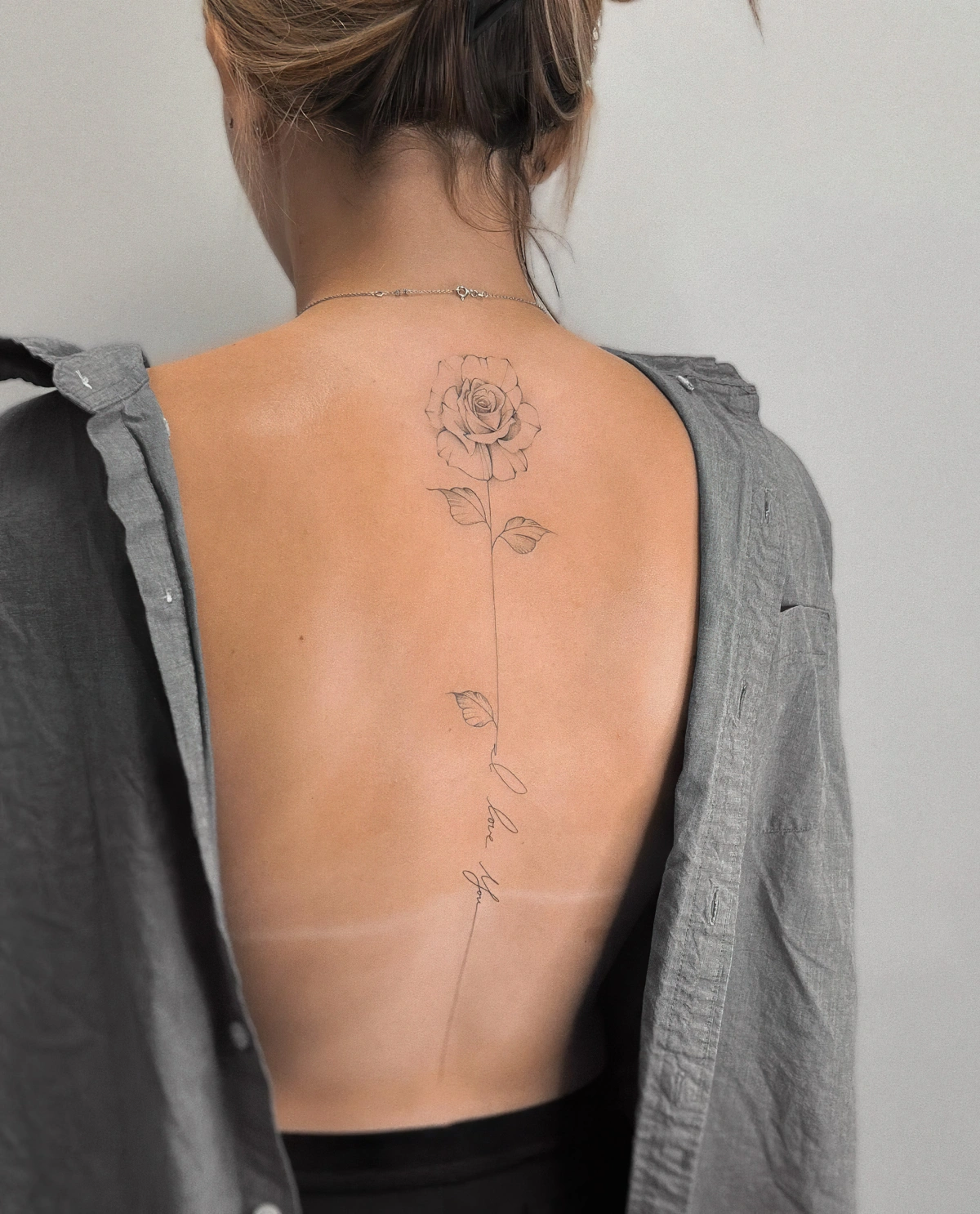 tatouage fin femme dessin rose delicat tige longue petales feuilles ecriture
