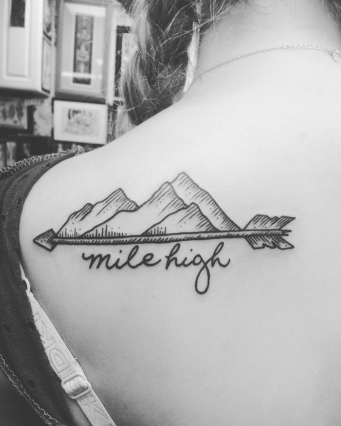 tatouage féminin, flèche et montagne, scrip tatoué au dos sous l'épaule