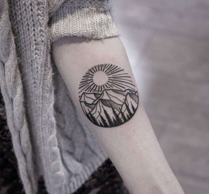 tatouage minimaliste femme, dessin rond, soleil rayonnant et chaîne de montagnes