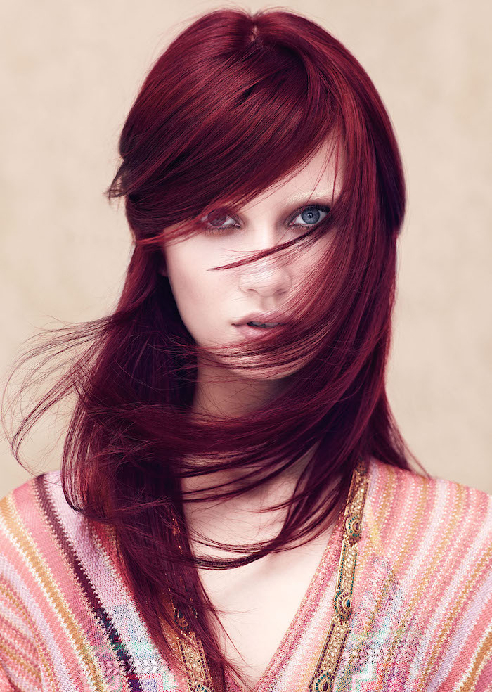 cheveux rouge foncé, coloration bordeaux, coiffure avec frange du côté, robe ethnique en rose et or, cheveux raids