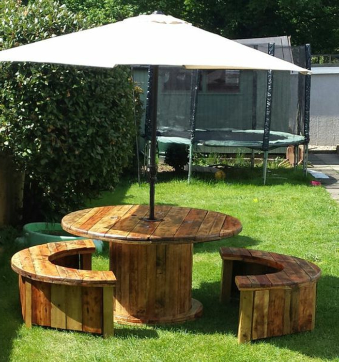 amenagement jardin récup, deco touret table et bancs en bois, demi cercle, un parasol qui passe par le centre, gazon vert