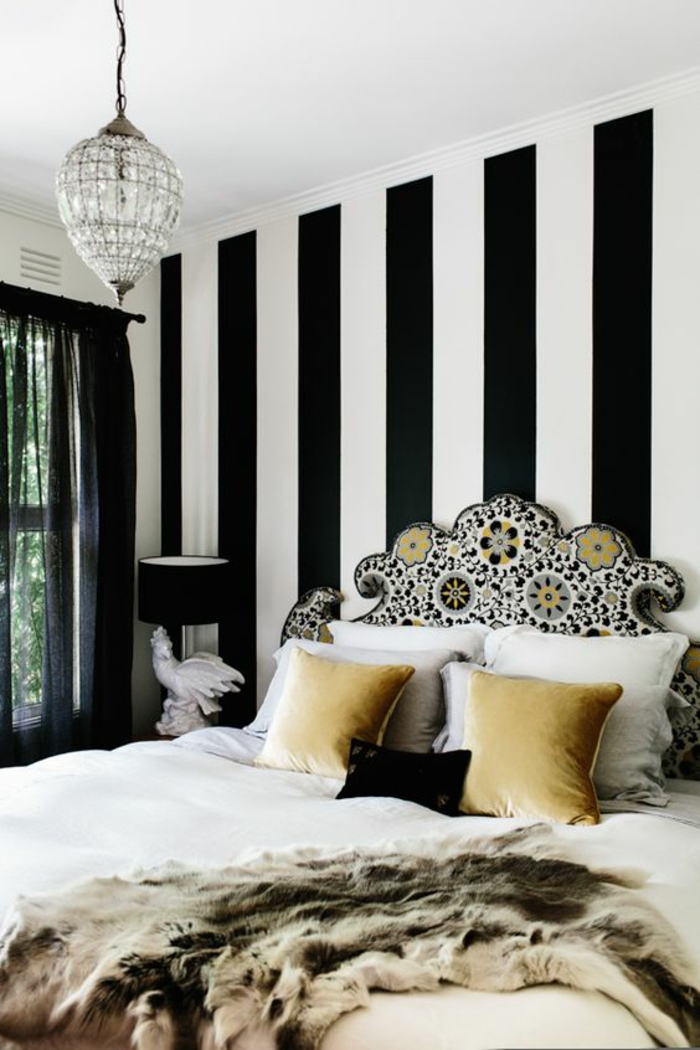déco chambre adulte avec les murs aux rayures noires et blanches lustre en vrystal dossier du lit richement orné en motifs floraux colorés 
