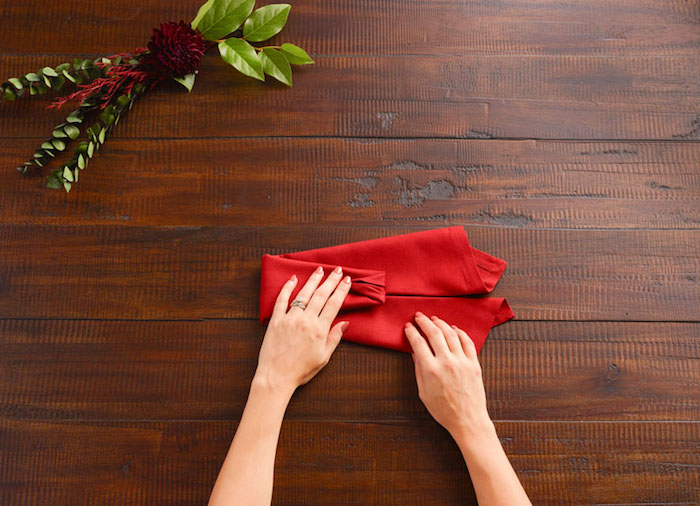 décoration de table de noel, technique origami avec nappe rouge, bouquet de feuilles vertes