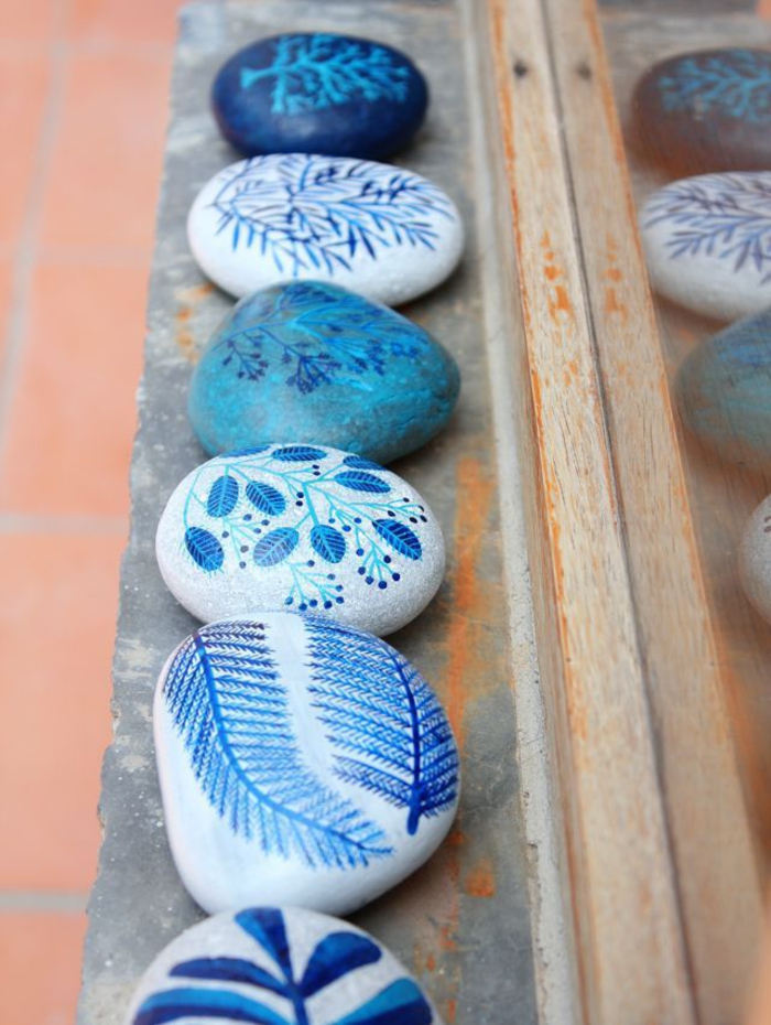 une jolie idée déco avec des galets peints à motifs végétaux aux nuances de bleu 