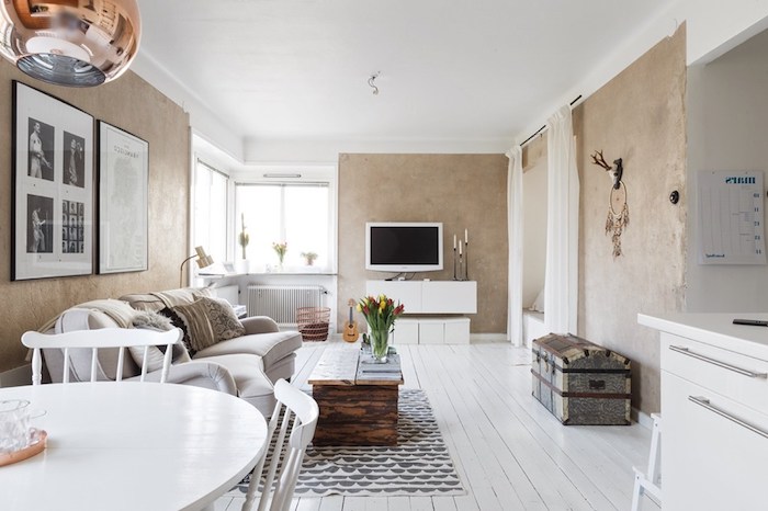 intérieur scandinave, parquet en bois peint en blanc, table basse en bois avec vase et tulipes, canapé beige en cuir
