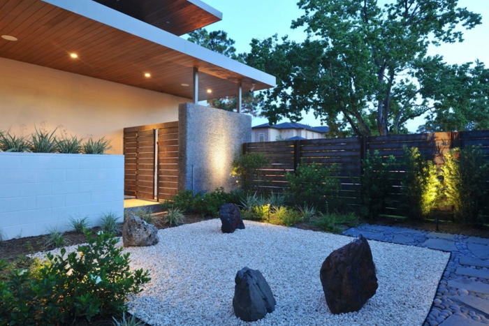 déco de jardin zen moderne, maison moderne, coin recouvert de gravier et grosses pierres, arbres et arbustes, éclairage exterieur