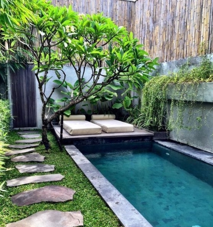 idee deco ajrdin zen japonais avec un petit bassin d eau, chemin de peirres sur un gazon vert, arbre à couronne verte, bambou, matelas îlot coin détente