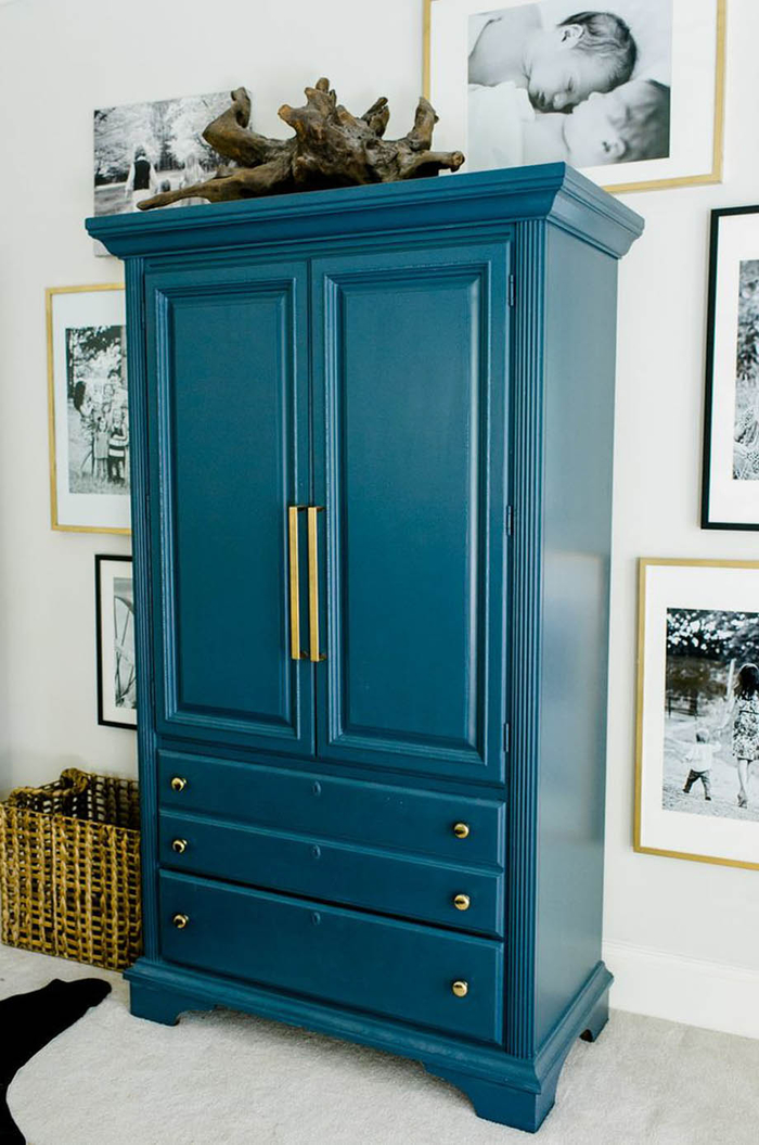 une jolie armoire peint bleu paon foncé mise en valeur par une galerie photos en noir et blanc