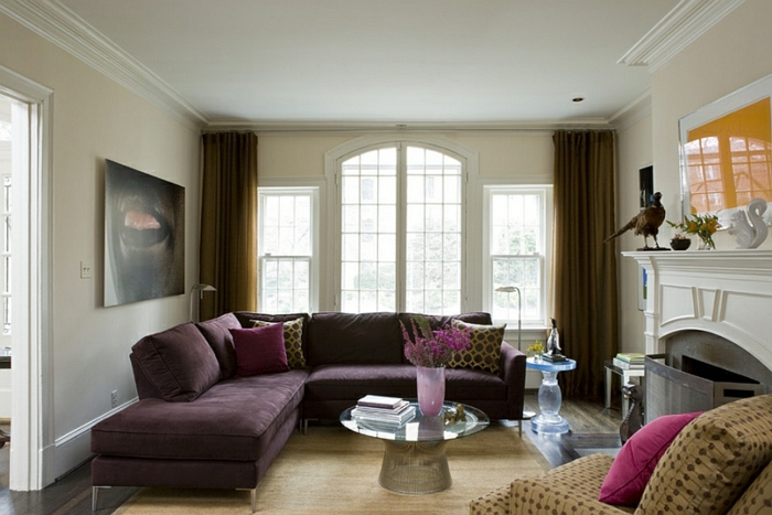 aubergine couleur, sofa d'angle pourpre, deux tables rondes de salon, cheminée décorative, tableau abstrait