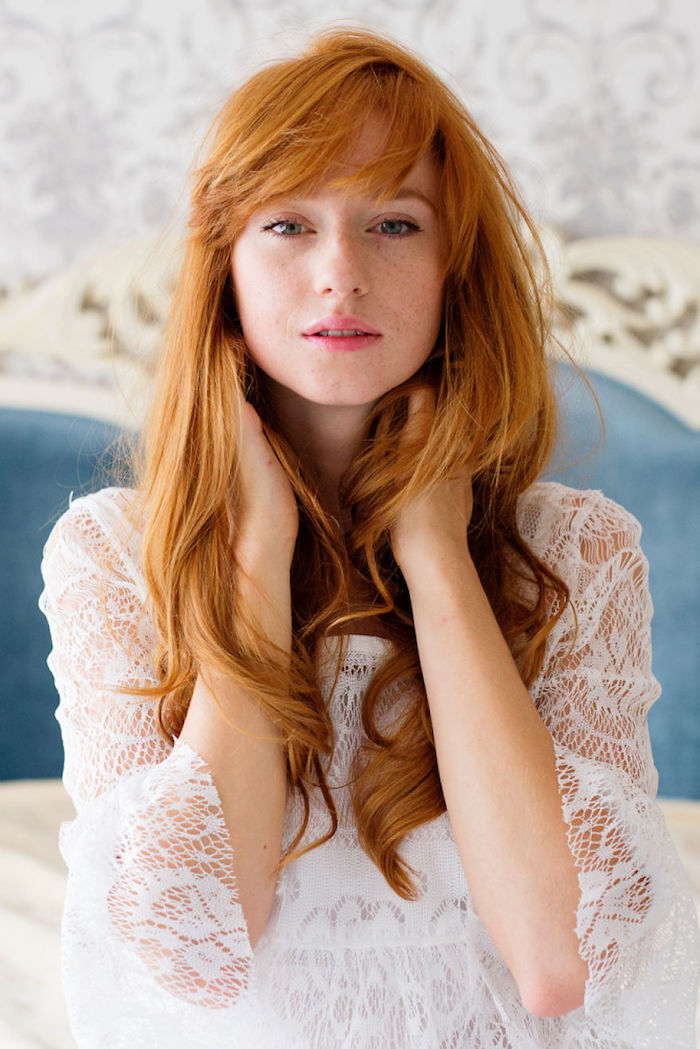 couleur rousse, tête de lit en blanc et bleu, femme aux cheveux longs et bouclés, maquillage naturel avec lèvres rose