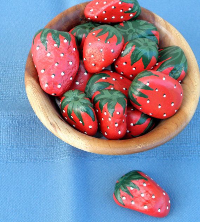 des galets peints en fraises qui semblent très réelles