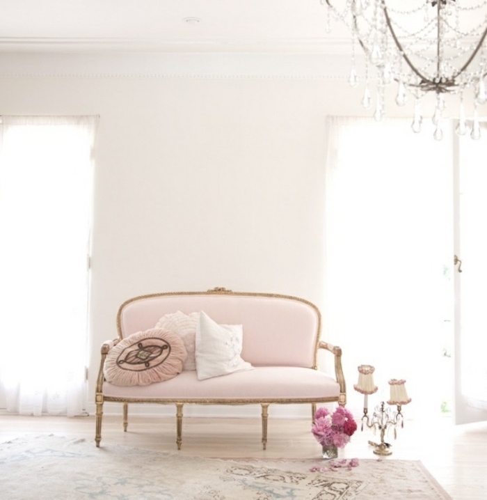 canapé shabby chic couelur rose, tapis vintage usés, bouquet de fleurs, lustre baroque et mur couleur blanche