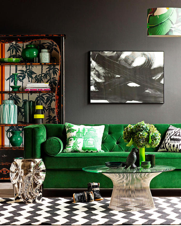 tissu velours, salon aux murs gris, bibliothèque orange à motifs tropicales, canapé en velours vert, peinture en blanc et noir