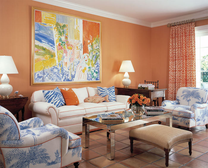 deco moderne, tabouret en cuir marron avec pieds en bois, canapé blanc avec contours orange, bouquet de roses orange, rideaux longs à motifs ethniques