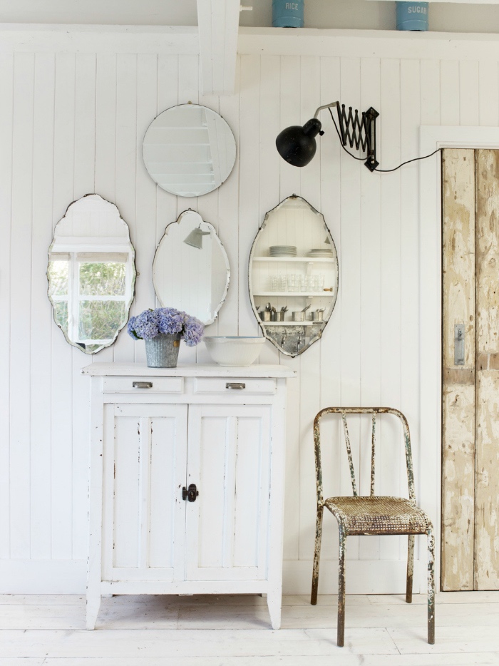 style shabby chic récup, meuble de rangement blanc, lambris blanc, deco murale de miroirs vintage, porte en planches de bois, chaise en métal rouillée